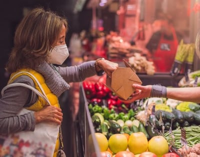 Une dame fait ses courses dans un commerce de proximité.